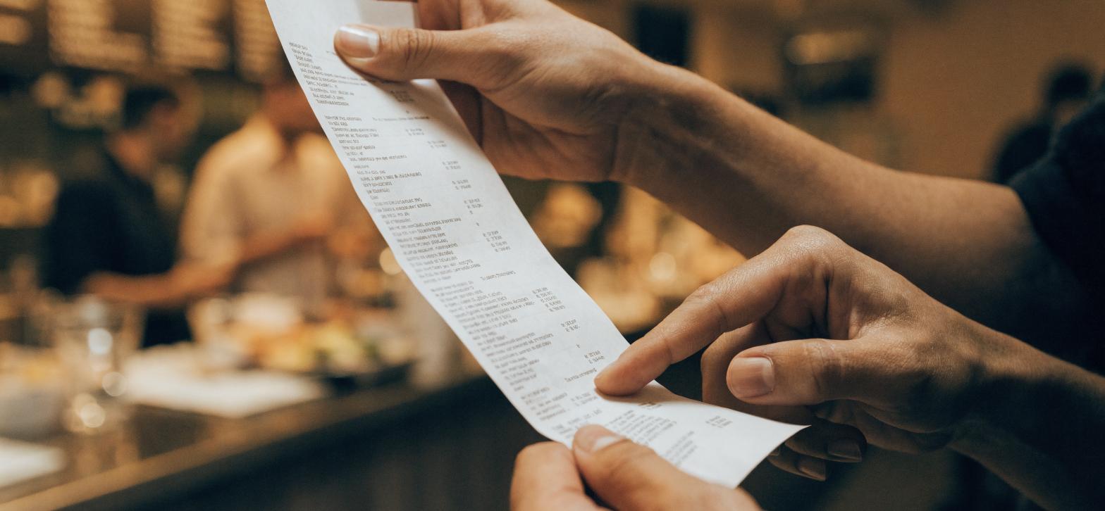Hands holding a deli receipt and pointing to the lower section where the McAlisters survey code used to be printed